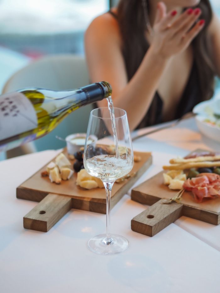Woman enjoying wine with a cheese and charcuterie board, emphasizing elegance and leisure.