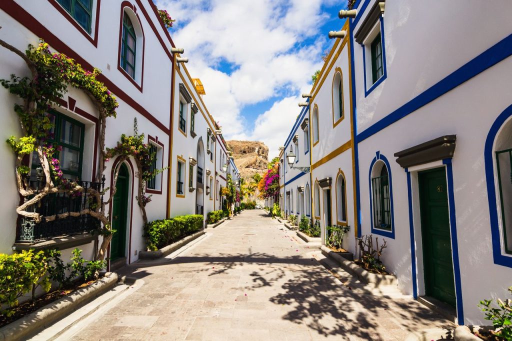 Charming Mediterranean street with vibrant architecture and flowering vines under a blue sky.